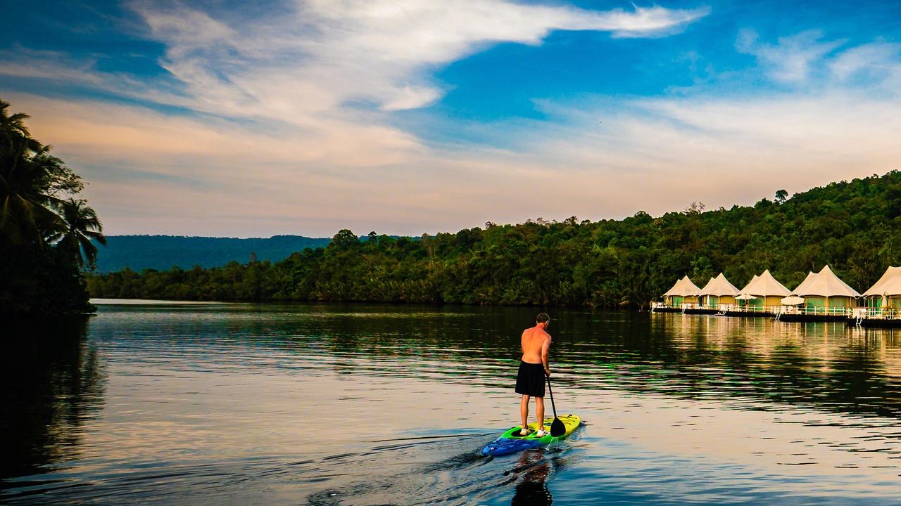 Man paddle boarding on river at 4 Rivers Floating Lodge