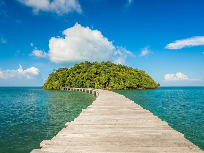 Wooden boardwalk over the sea leads to green jungle at Song Saa