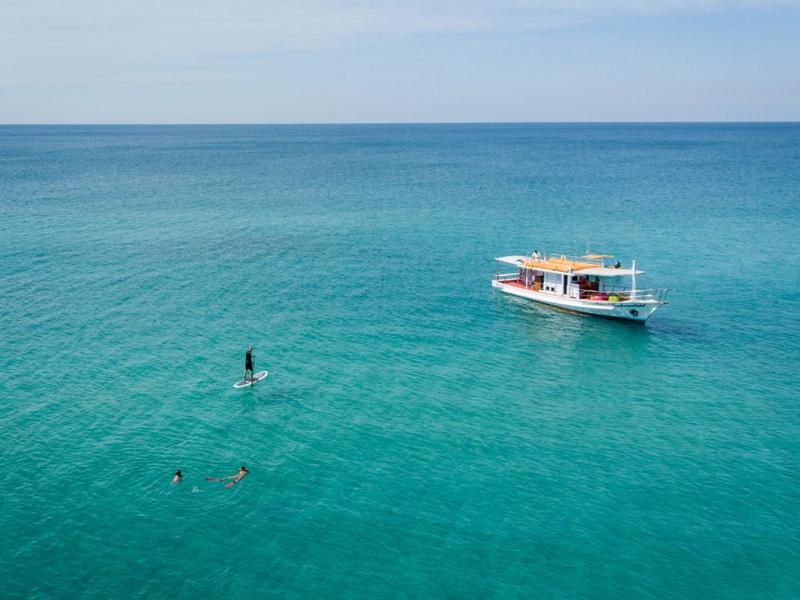 Blue ocean with a boat and paddle-boarder